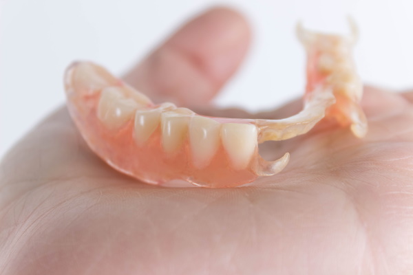 flexible nylon denture on female hand. Removable dentures flexible, devoid of nylon, hypoallergenic